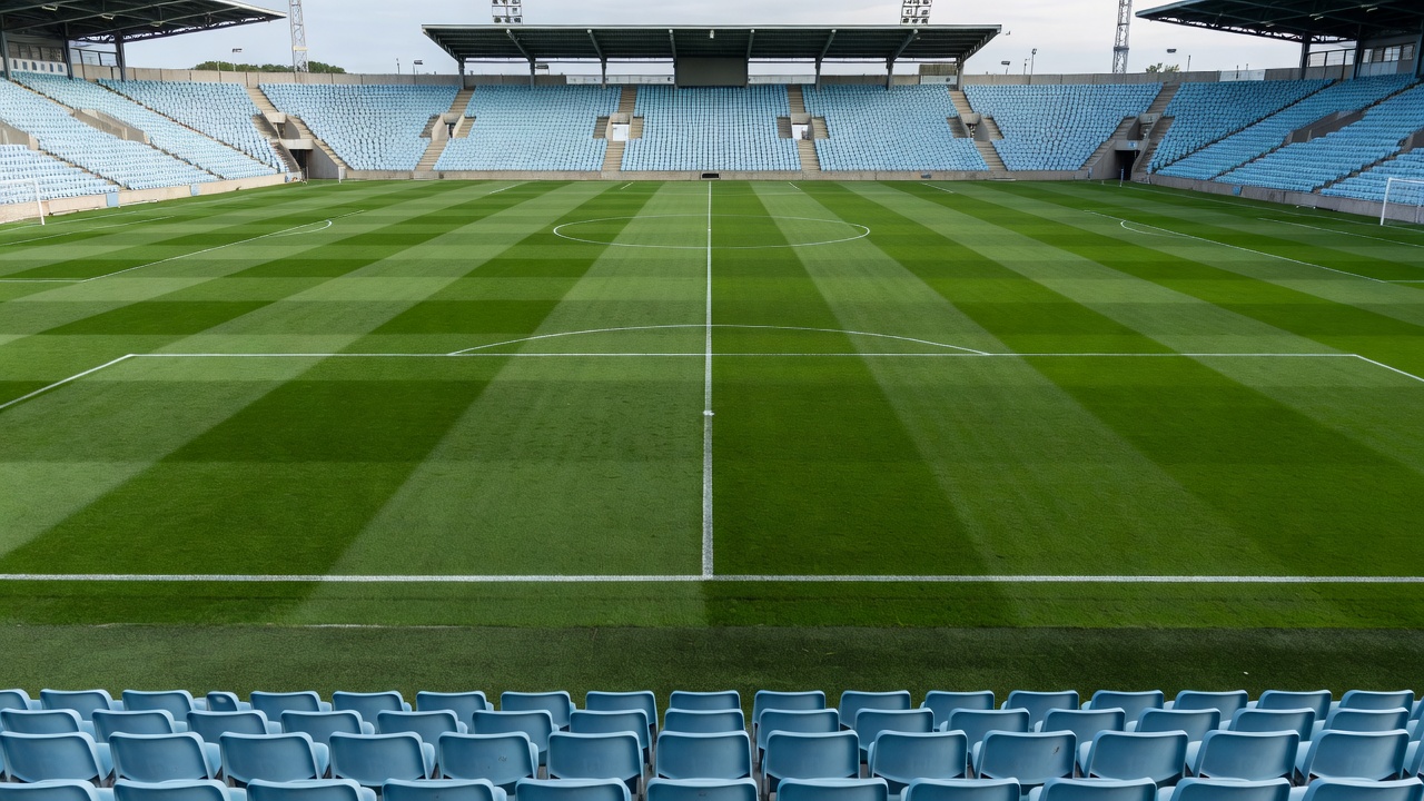Football pitch bordered by rows of pale blue stadium seats in Malmö